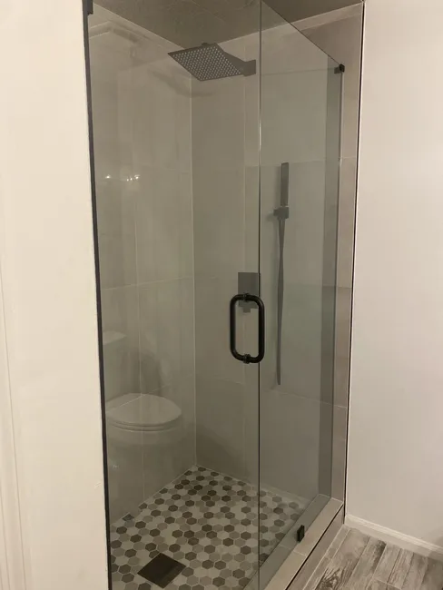 2 Panel Frameless Glass Shower Enclosure with Matte Black Hinges, Clips, and Handle.