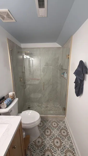 A custom 2-panel swinging door shower enclosure with elegant brushed bronze hardware enhances the bathroom's appeal.