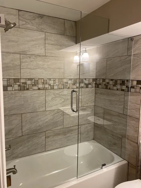 A two panel frameless enclosure, with chrome hardware on top of a tub