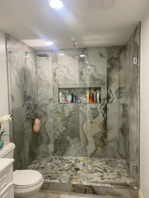 2 Panel Frameless Glass Shower with Chrome Hinges and Handle. Swing door is on the right and the left is a fixed panel.