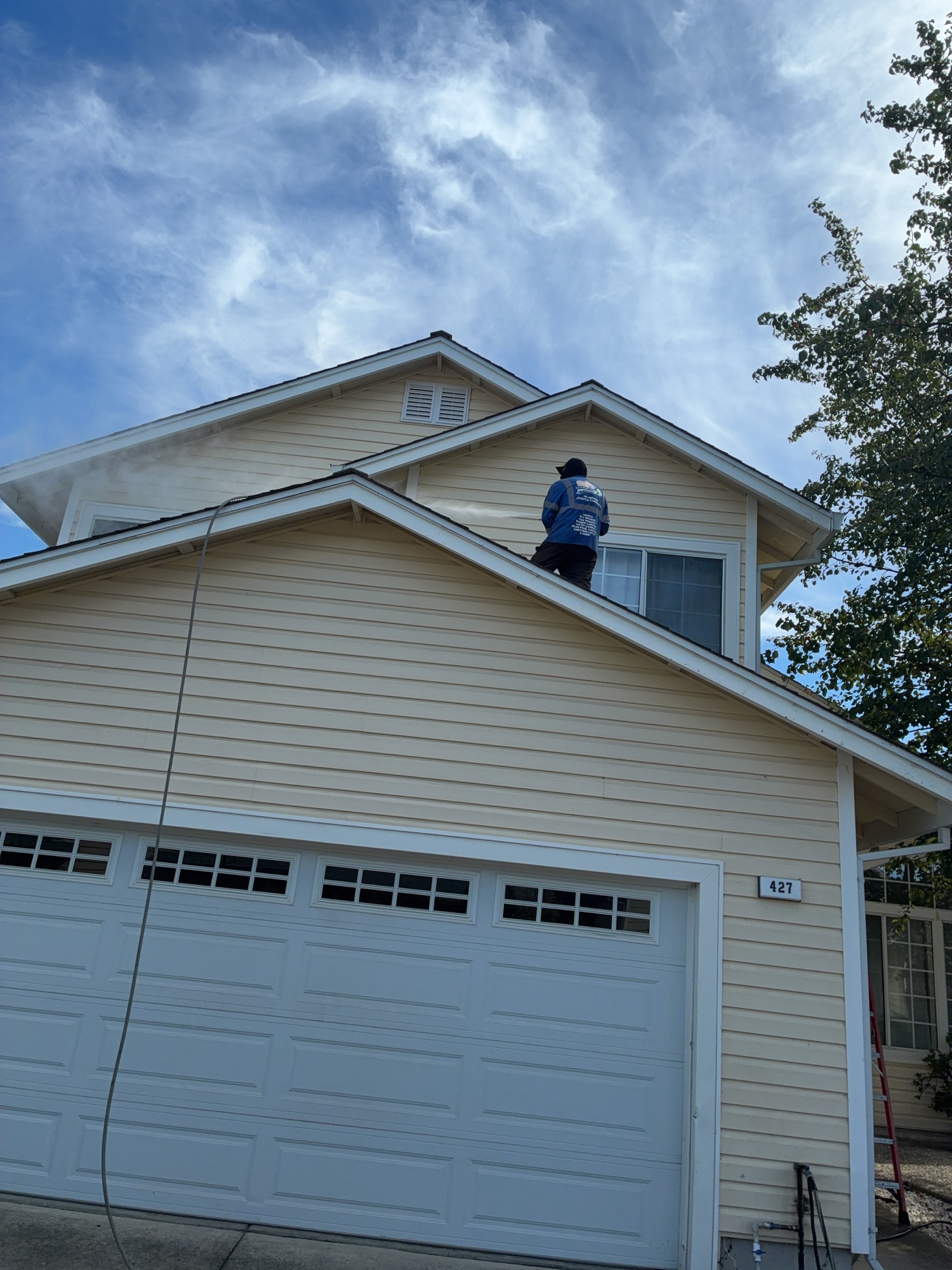 Technician cleaning the upper walls of a two-story house