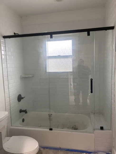 (2) Three Panel Frameless Sliding Glass Shower Enclosures installed over bath tubs with Matte Black Sliders, Clips, and Handles