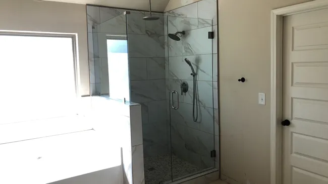 Elevating the master suite, we installed a clear tempered glass door with brushed nickel accents for a sleek finish.