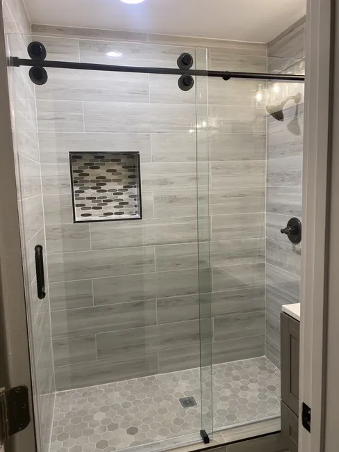 (2) Two Panel Frameless Crescent Sliding Glass Shower Enclosures - installed with a Matte Black Hardware Finish in both showers