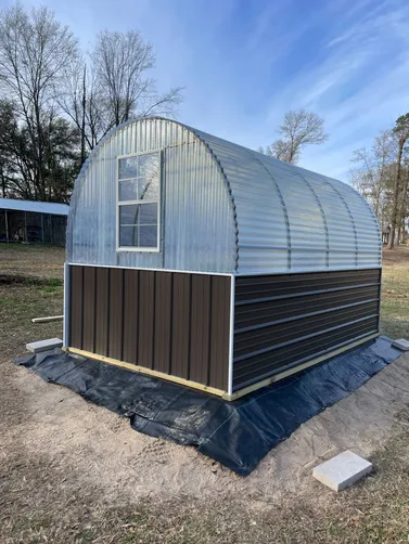 photo at Marshall, TX on Jan 20, 2026: 8x12 Greenhouse with welded steel frame, treated shelving, window, storm doorBurnished Slate with 